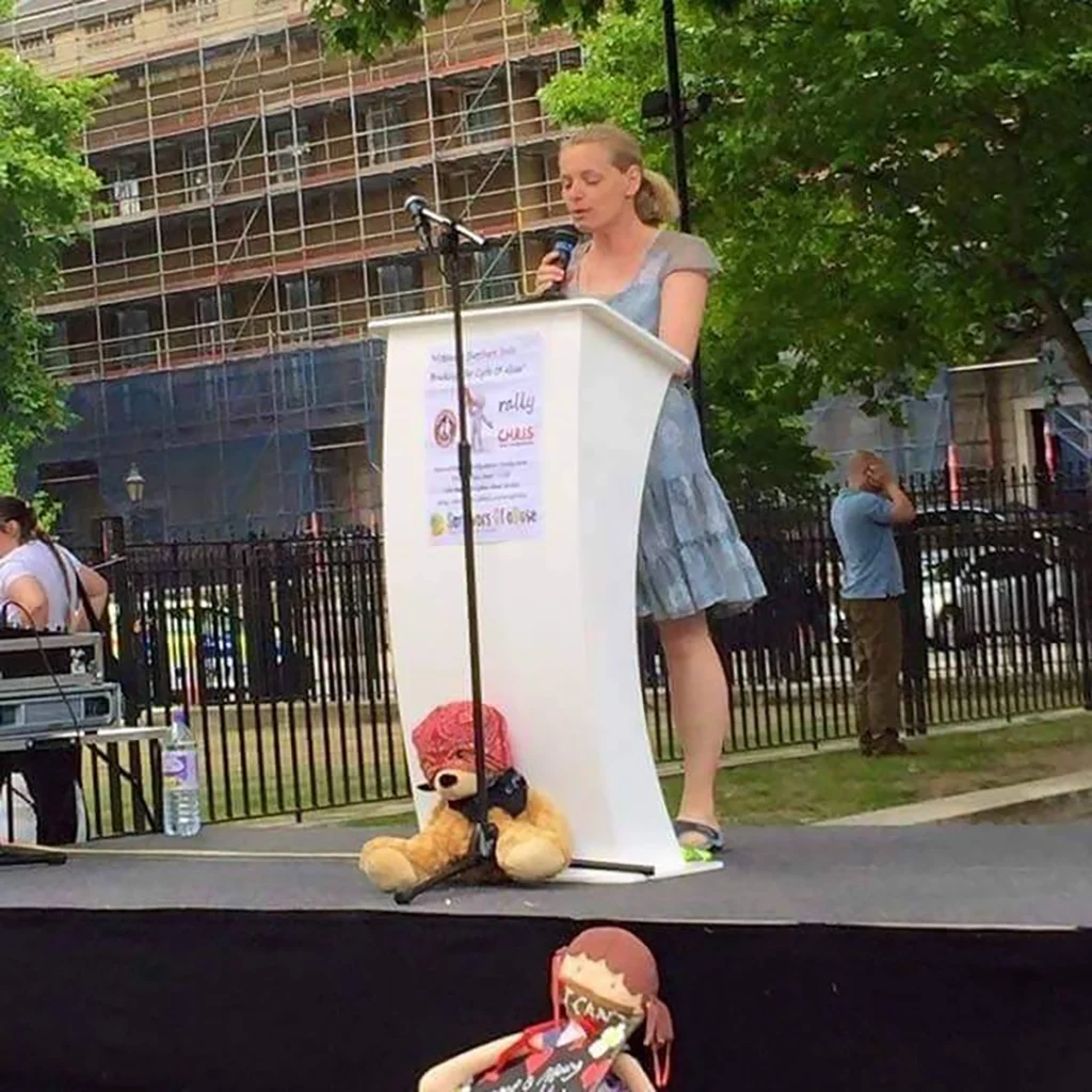 Chris Tuck speaking at a rally at a lectern for Survivors Of aBuse